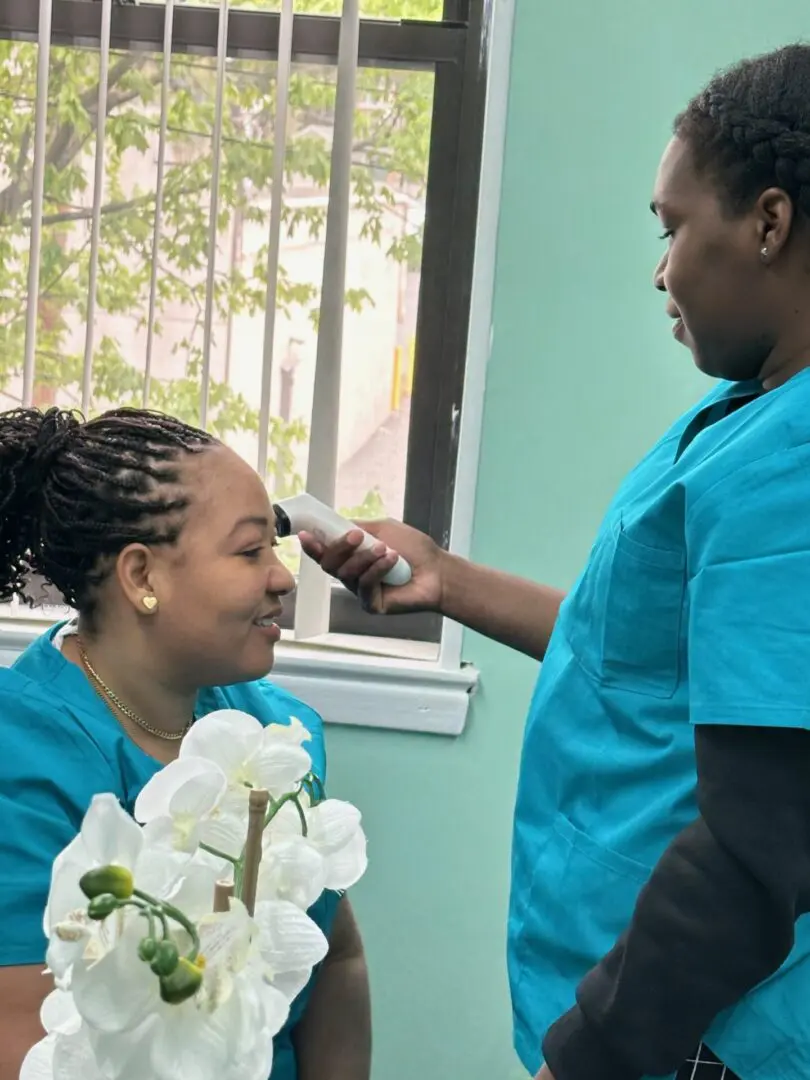 A woman in blue scrubs is getting her hair cut.